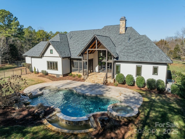 rear view of property featuring a sunroom, a pool with hot tub, and a patio area