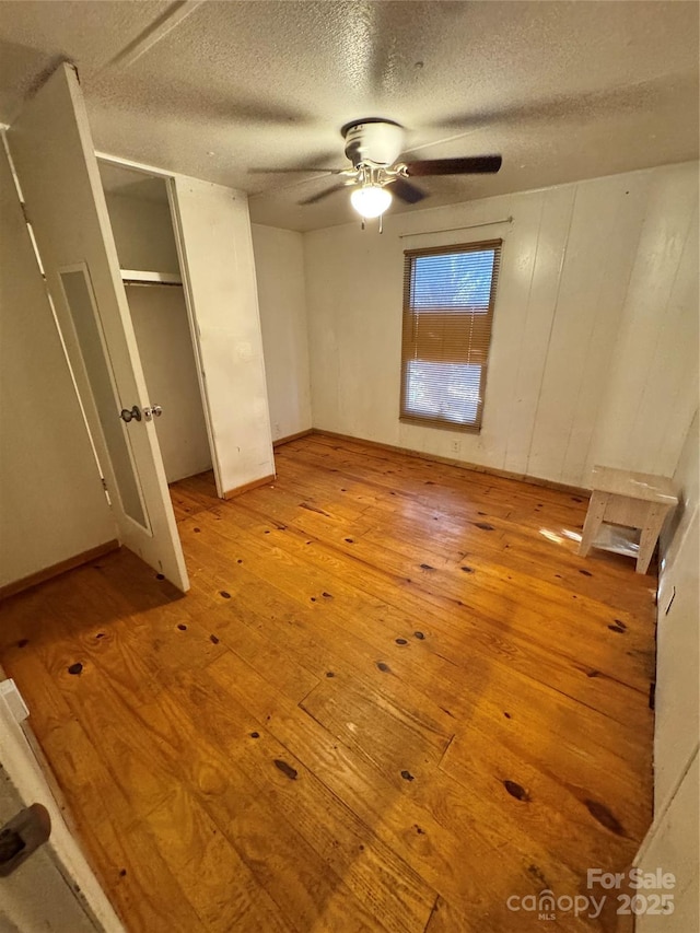 unfurnished bedroom with a textured ceiling, light wood-type flooring, and ceiling fan