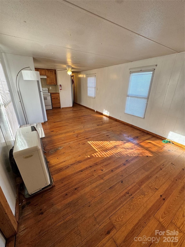 unfurnished living room featuring ceiling fan, wood-type flooring, and a textured ceiling