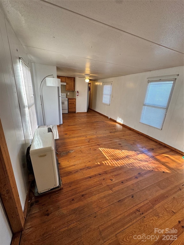 unfurnished living room with ceiling fan, wood-type flooring, and a textured ceiling