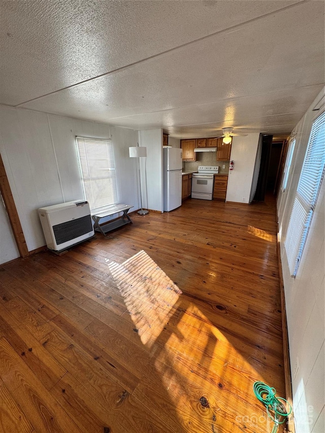 unfurnished living room featuring a textured ceiling, dark hardwood / wood-style flooring, and heating unit