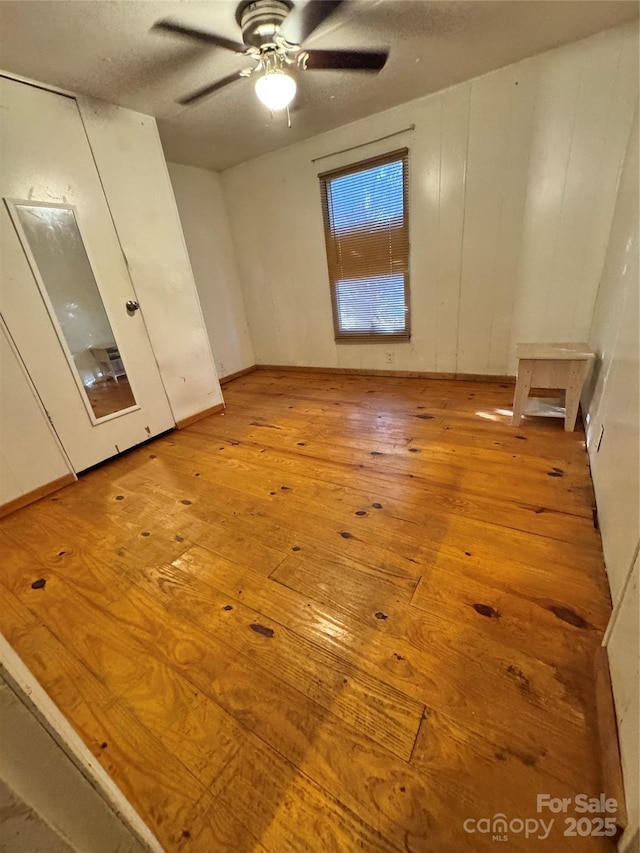 unfurnished room featuring ceiling fan, light hardwood / wood-style flooring, and a textured ceiling