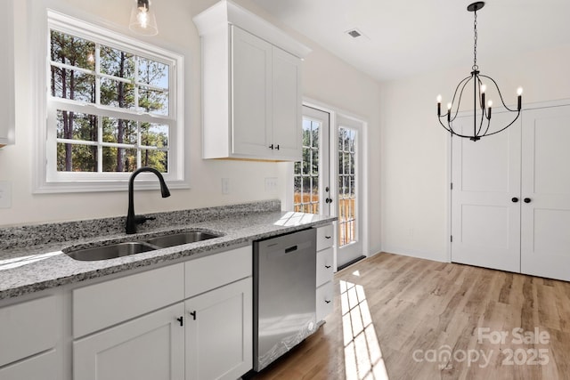 kitchen with stainless steel dishwasher, a sink, visible vents, and light wood-style floors