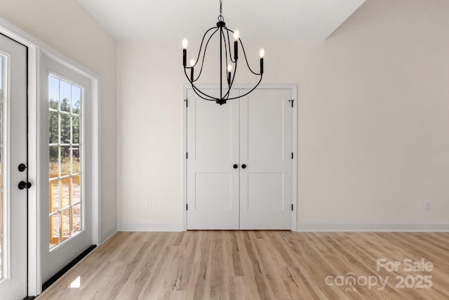 unfurnished dining area with light wood-style floors, baseboards, and a chandelier