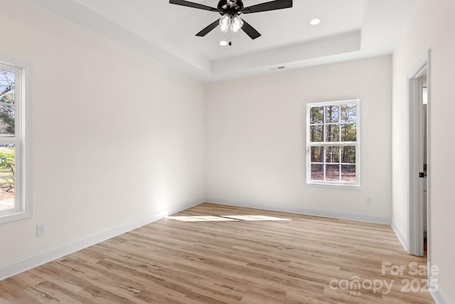 empty room with baseboards, a ceiling fan, wood finished floors, a tray ceiling, and recessed lighting