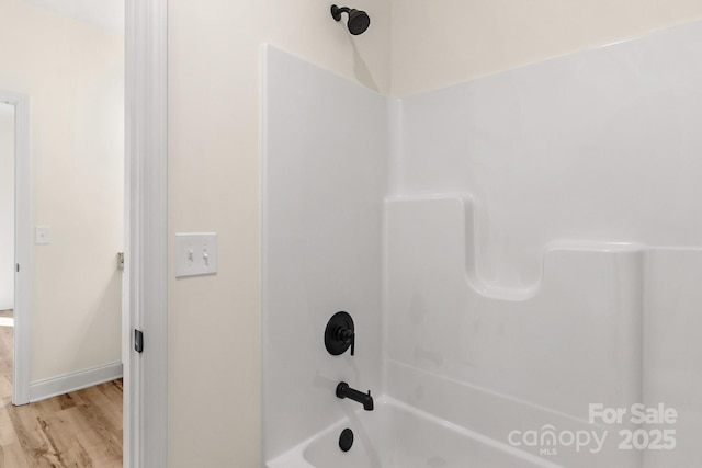 bathroom featuring  shower combination, baseboards, and wood finished floors