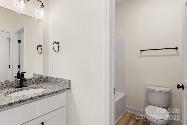 full bath with baseboards, vanity, toilet, and wood finished floors