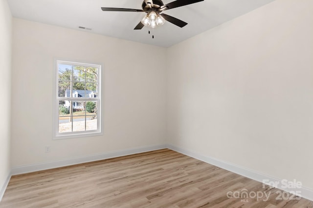 empty room featuring light wood finished floors, a ceiling fan, visible vents, and baseboards