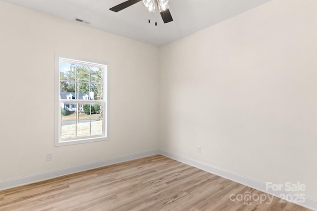 spare room featuring a ceiling fan, visible vents, light wood-style flooring, and baseboards