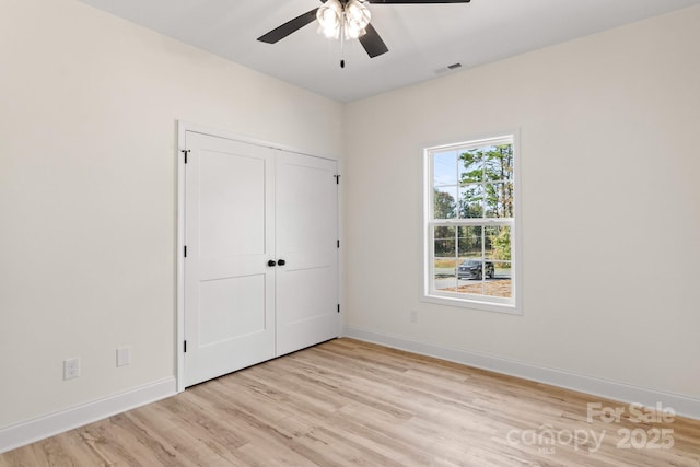 unfurnished bedroom featuring a ceiling fan, visible vents, baseboards, a closet, and light wood finished floors