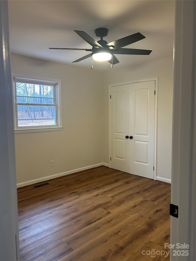 unfurnished bedroom featuring ceiling fan, dark wood-type flooring, and a closet