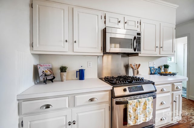 kitchen with backsplash, ornamental molding, stainless steel appliances, dark hardwood / wood-style floors, and white cabinetry