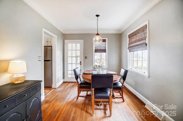 dining area with light hardwood / wood-style flooring and ornamental molding