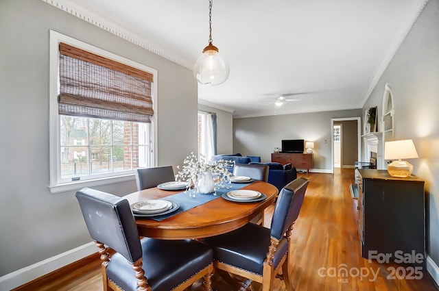 dining space with hardwood / wood-style floors, ceiling fan, crown molding, and built in shelves