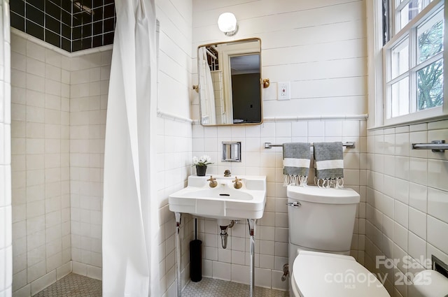 bathroom with a shower with curtain, toilet, sink, and tile walls