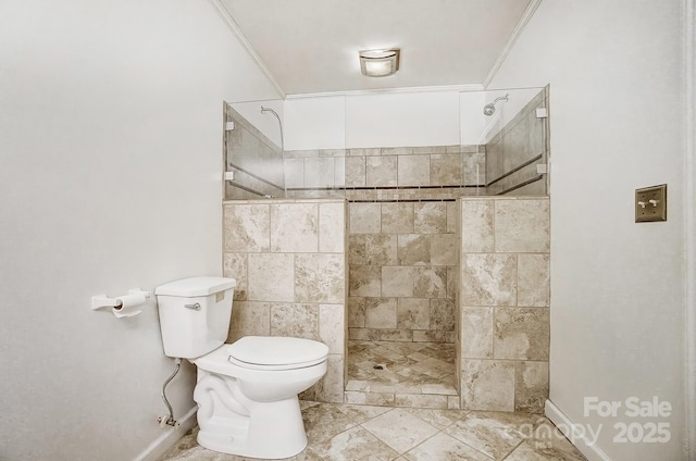 bathroom featuring toilet, ornamental molding, and tiled shower