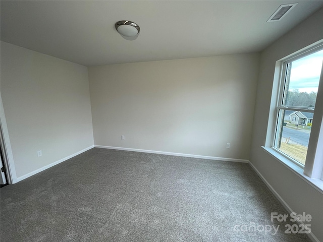 unfurnished room featuring baseboards, visible vents, and dark colored carpet