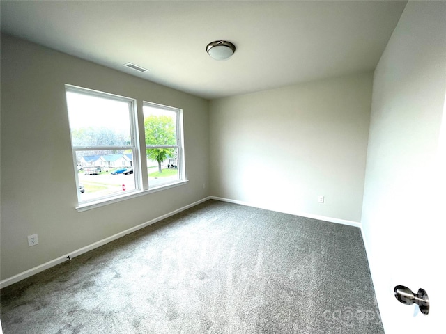 carpeted spare room featuring baseboards and visible vents