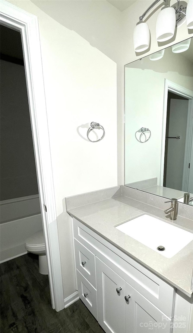 full bath featuring wood finished floors, vanity, and toilet