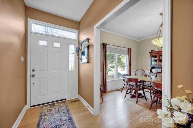 entrance foyer featuring crown molding and light wood-type flooring