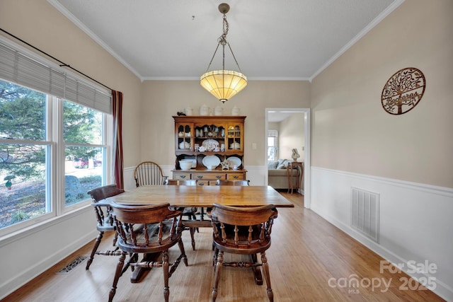 dining area with light wood-type flooring and ornamental molding