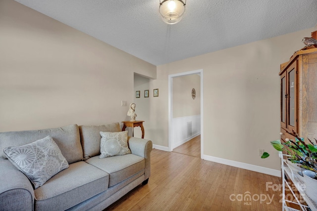 living room with light hardwood / wood-style floors and a textured ceiling