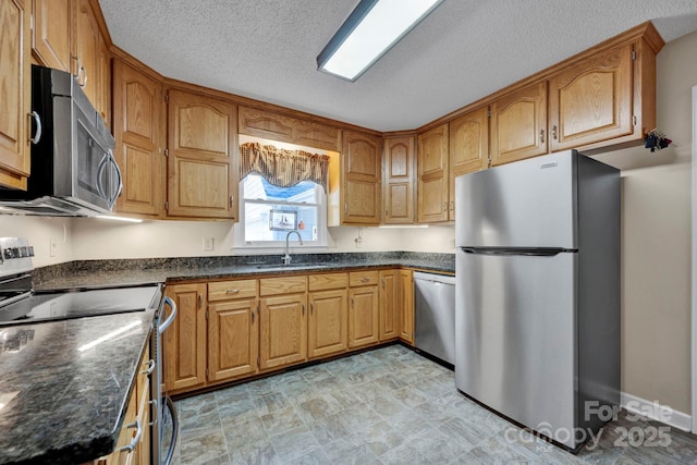 kitchen with dark stone countertops, sink, a textured ceiling, and appliances with stainless steel finishes