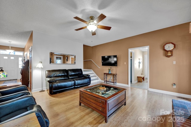 living room with a textured ceiling, light wood-type flooring, and ceiling fan