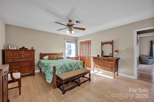 bedroom featuring ceiling fan, light hardwood / wood-style floors, and a textured ceiling