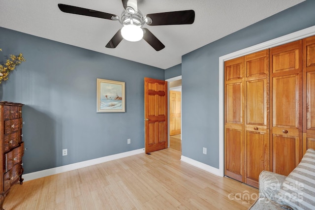 bedroom featuring ceiling fan, a closet, a textured ceiling, and light hardwood / wood-style flooring