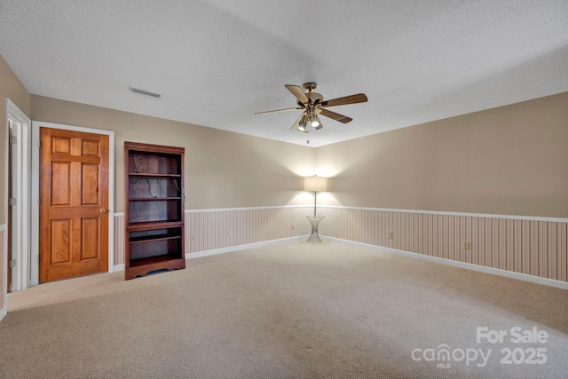 carpeted empty room with ceiling fan and a textured ceiling