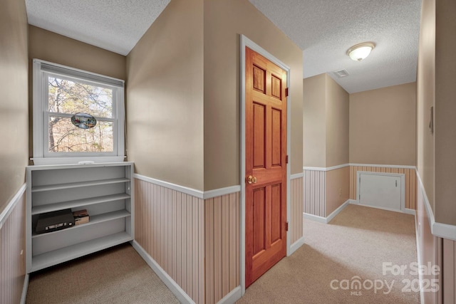 hallway featuring a textured ceiling and light carpet