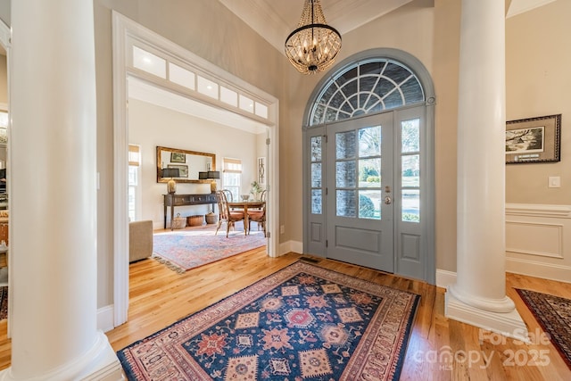 entrance foyer with decorative columns, an inviting chandelier, and hardwood / wood-style flooring