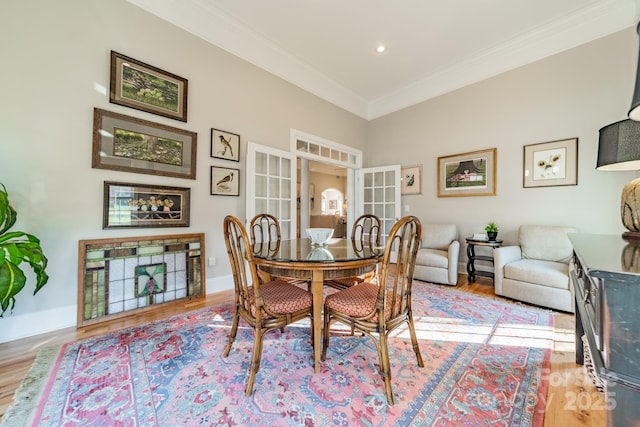 dining space featuring french doors, light wood-type flooring, and ornamental molding