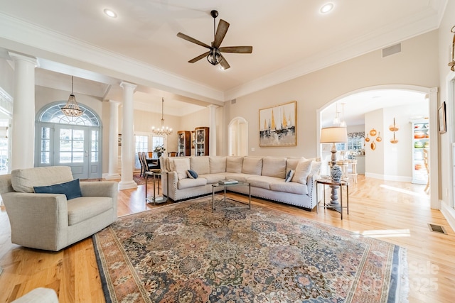 living room with ceiling fan with notable chandelier, light hardwood / wood-style floors, and ornamental molding