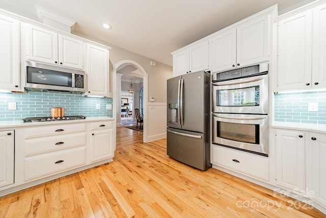 kitchen featuring backsplash, stainless steel appliances, white cabinetry, and light hardwood / wood-style floors