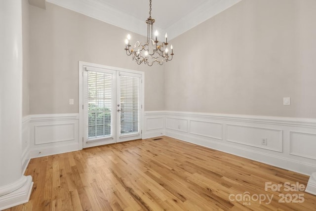 4150 Summit Ridge Ln, Denver, NC 28037 - unfurnished dining area featuring a chandelier, a wainscoted wall, ornamental molding, light wood-style floors, and a decorative wall