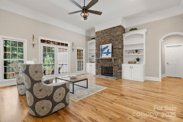4150 Summit Ridge Ln, Denver, NC 28037 - living room featuring ornamental molding, a ceiling fan, light wood-style flooring, a stone fireplace, and built in shelves