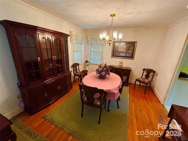 dining area with hardwood / wood-style floors, a notable chandelier, and ornamental molding