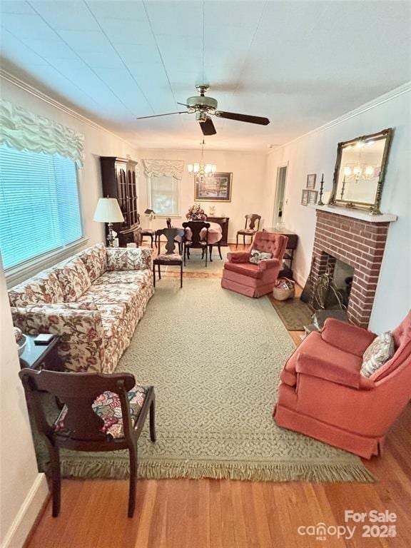 living room with a fireplace, ceiling fan with notable chandelier, a wealth of natural light, and ornamental molding