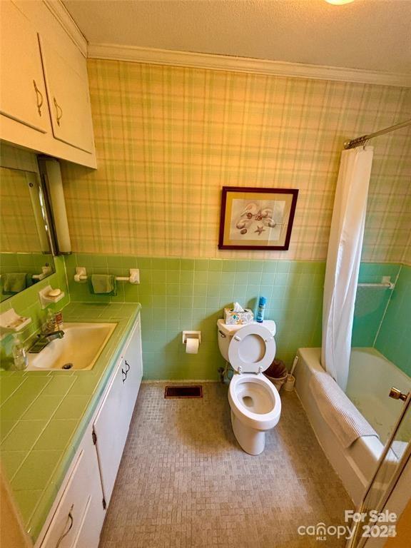 full bathroom featuring toilet, shower / bathtub combination with curtain, tile walls, and ornamental molding