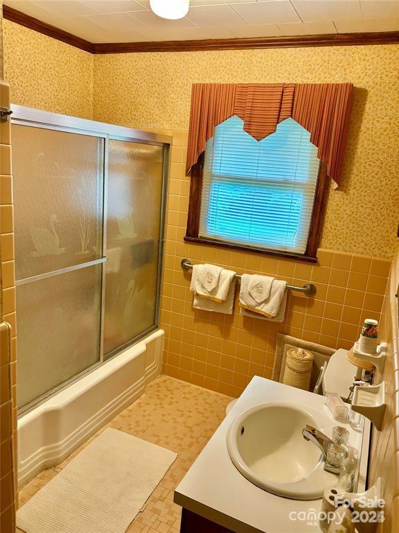 bathroom with enclosed tub / shower combo, tile patterned floors, vanity, tile walls, and ornamental molding