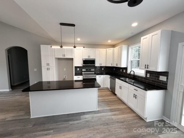 kitchen featuring white cabinets, sink, decorative light fixtures, a kitchen island, and stainless steel appliances