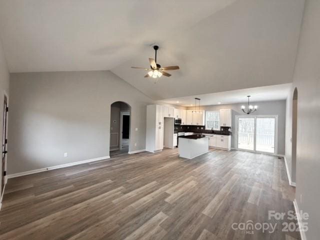 unfurnished living room featuring hardwood / wood-style floors, ceiling fan with notable chandelier, and lofted ceiling