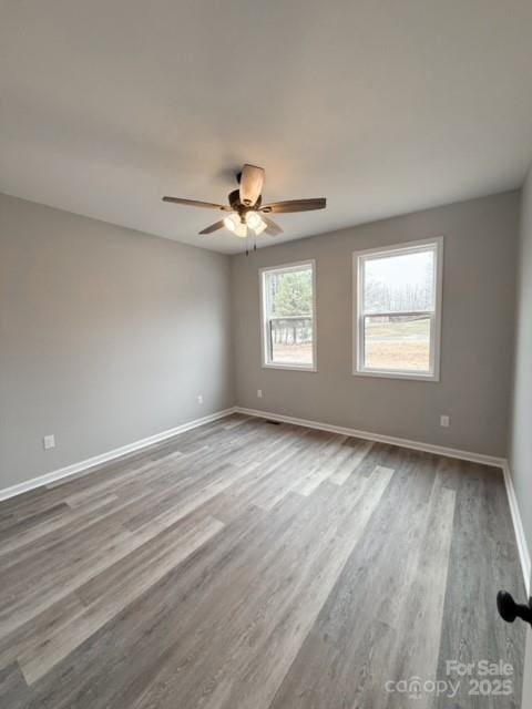 empty room with hardwood / wood-style floors and ceiling fan