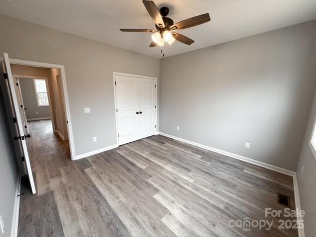 unfurnished bedroom with hardwood / wood-style floors, a closet, and ceiling fan