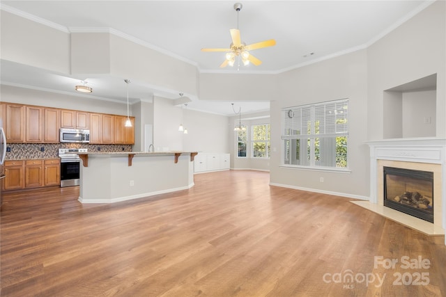 kitchen featuring tasteful backsplash, ornamental molding, appliances with stainless steel finishes, and a breakfast bar area