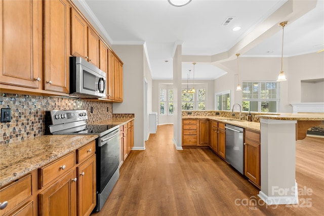 kitchen featuring pendant lighting, ornamental molding, stainless steel appliances, and a kitchen breakfast bar