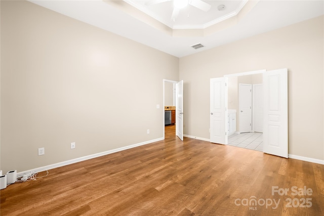 unfurnished bedroom featuring hardwood / wood-style floors, a tray ceiling, ornamental molding, and ceiling fan