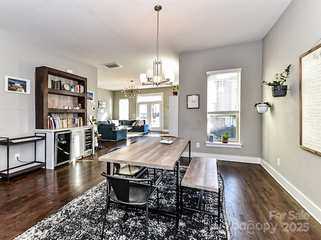 dining space with wine cooler, an inviting chandelier, a wealth of natural light, and dark wood-type flooring